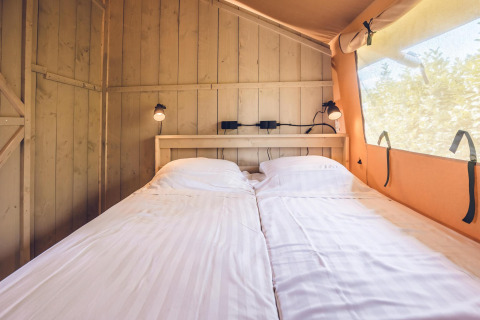 Indvendig udsigt af en safari telt 'Red Deer' med to enkeltsenge og hyggelig belysning ved Holiday park Ackersate.