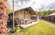 Safari-telt 'Vos' med træterrasse og havemøbler i ferieland Ackersate i Holland, omgivet af grønne hække.