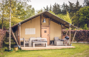 Tenda safari 'Vos' al parco vacanze Ackersate nei Paesi Bassi con arredi da esterno e tanto verde.