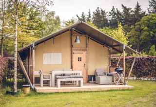 Tenda safari 'Vos' al parco vacanze Ackersate nei Paesi Bassi con arredi da esterno e tanto verde.