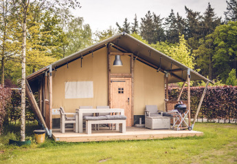 Tenda safari 'Vos' al parco vacanze Ackersate nei Paesi Bassi con arredi da esterno e tanto verde.