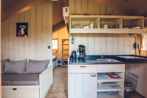 Interieur van safaritent 'Vos' op vakantiepark Ackersate in Nederland, met keuken en zithoek.