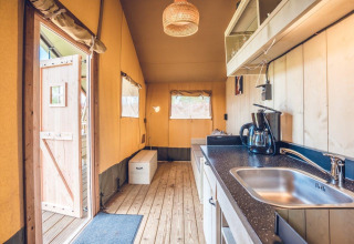 Binnenzicht van safaritent 'Vos' in vakantiepark Ackersate in Nederland met keuken en zitruimte.