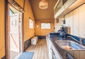 Indvendig udsigt af Safari-telt 'Vos' i Holiday park Ackersate, Holland, viser et hyggeligt køkken og opholdsområde.