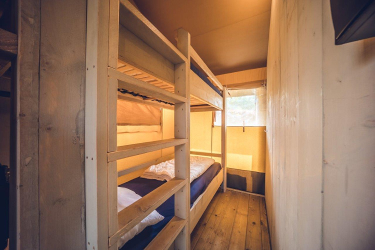 Innenraum des Safari-Zelts 'Vos' im Ferienpark Ackersate, mit Etagenbetten und Holzwänden.