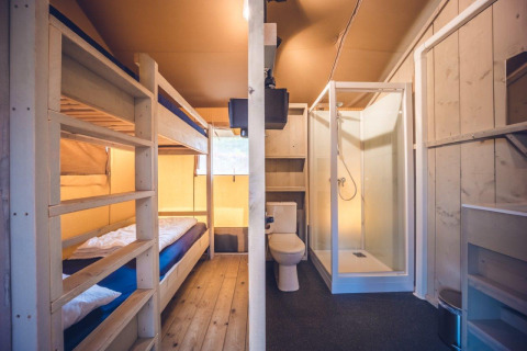 Interieur van safaritent 'Vos' bij vakantiepark Ackersate in Nederland, met stapelbedden en douche.