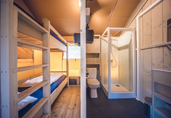 Interieur van safaritent 'Vos' op vakantiepark Ackersate in Nederland, met stapelbedden en badkamer.