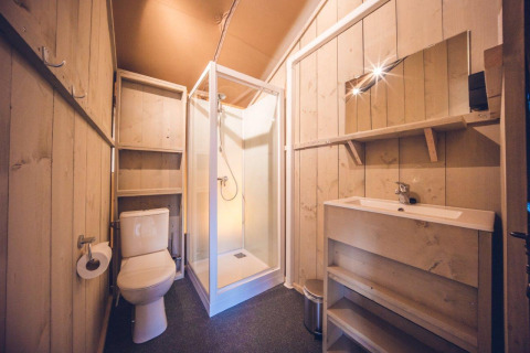 Baño en la tienda safari 'Vos' en el parque de vacaciones Ackersate, Países Bajos, con ducha, inodoro y lavabo.