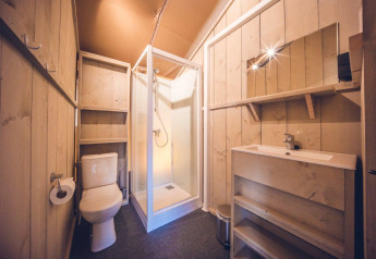 Badkamer in safaritent 'Vos' op vakantiepark Ackersate in Nederland, met douche, toilet en wastafel.