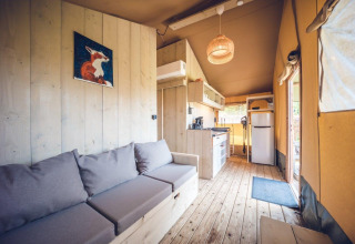 Safaritent 'Vos' op Holiday park Ackersate in Nederland, houten inrichting, keukenhoek en zetel.