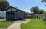 Modern tiny house at Holiday park Ackersate, Netherlands, with lush lawn, patio area, and outdoor seating.