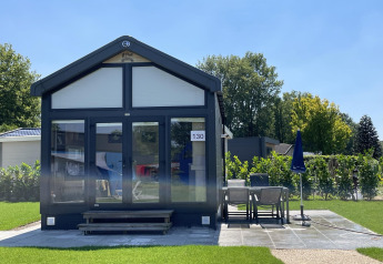 Tiny house at Holiday park Ackersate in the Netherlands, with patio and garden furniture on a sunny day.