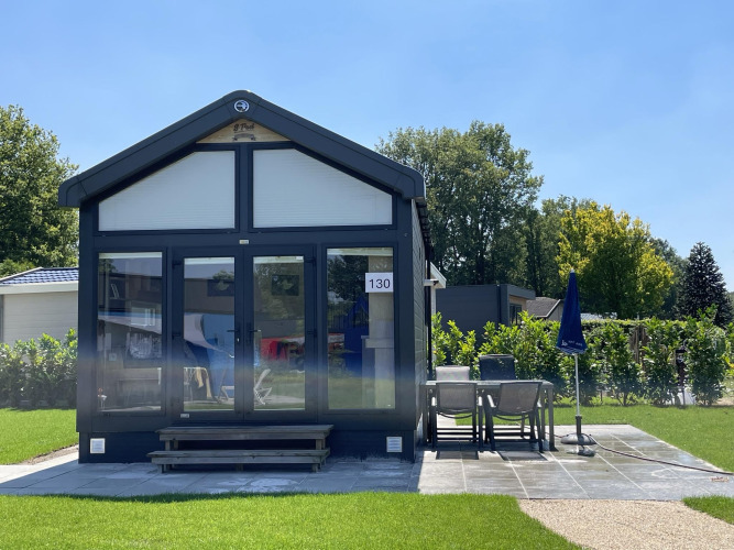 Tiny house at Holiday park Ackersate in the Netherlands, with patio and garden furniture on a sunny day.