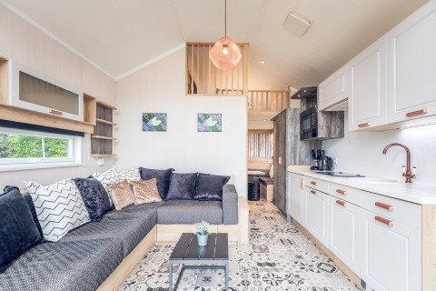 Interno moderno di una tiny house al Holiday park Ackersate nei Paesi Bassi, con cucina e soggiorno accogliente.
