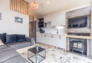 Bright, modern tiny house interior at Holiday park Ackersate in the Netherlands, featuring sofa and kitchenette.