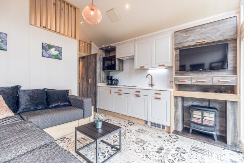 Lys og moderne stue og tekøkken i et tiny house på Holiday park Ackersate i Holland, med sofa og TV.