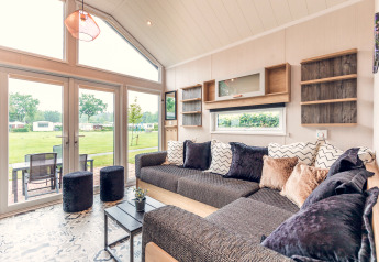 Lichte en moderne woonkamer in tiny house op Vakantiepark Ackersate, met grote ramen en uitzicht op groen.