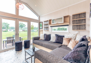 Luminoso soggiorno moderno in una tiny house al Holiday park Ackersate con grandi finestre e vista sul verde.