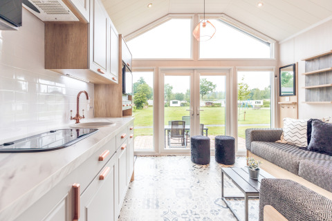Interno di una tiny house moderna all’Holiday park Ackersate, Paesi Bassi, con ampie finestre e vista verde.