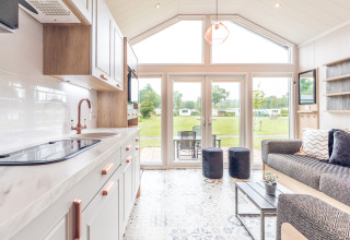 Interieur van een tiny house in Holiday park Ackersate, Nederland, met keuken en zicht op de tuin.