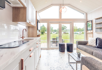 Interno di una tiny house moderna all’Holiday park Ackersate, Paesi Bassi, con ampie finestre e vista verde.