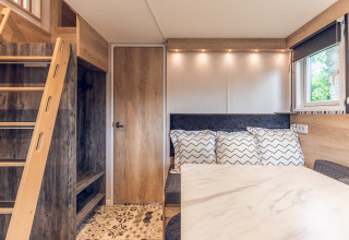 Interior moderno y acogedor de una tiny house en Holiday Park Ackersate con escalera, mesa y ventana visible.