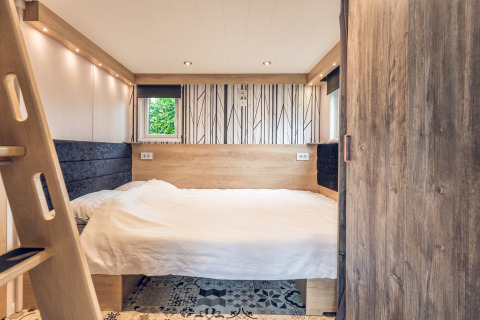 Dormitorio de tiny house en Holiday Park Ackersate, Países Bajos, con decoración de madera y cama doble.