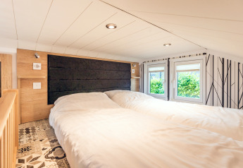 Cozy bedroom in a tiny house at Holiday Park Ackersate with two beds, low ceiling, and bright windows.