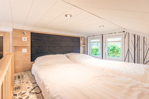 Camera accogliente in tiny house al Holiday Park Ackersate con due letti e finestre luminose.