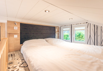 Camera accogliente in tiny house al Holiday Park Ackersate con due letti e finestre luminose.