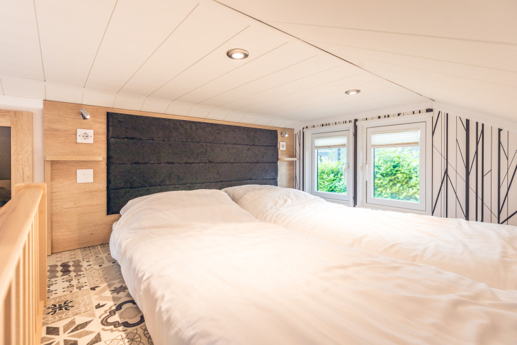Cozy bedroom in a tiny house at Holiday Park Ackersate with two beds, low ceiling, and bright windows.
