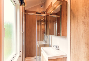 Salle de bain moderne avec éléments bois, douche et fenêtre dans une tiny house à Holiday park Ackersate.