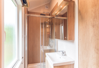 Modern bathroom with wood accents, shower enclosure and window in a tiny house at Holiday park Ackersate.