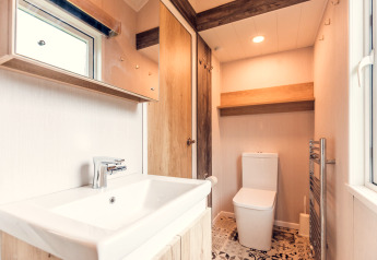 Baño luminoso en una tiny house en Holiday park Ackersate, Países Bajos, con lavabo y sanitario moderno.