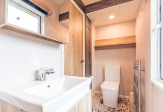 Baño luminoso en una tiny house en Holiday park Ackersate, Países Bajos, con lavabo y sanitario moderno.