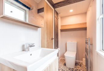 Bagno luminoso in una tiny house presso Holiday park Ackersate, Paesi Bassi, con lavabo e servizi igienici.