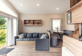 Modernes Wohnzimmer in einem Tiny House im Holiday Park Ackersate, Niederlande, mit grauem Sofa.