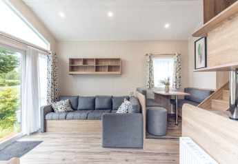 Modernes Wohnzimmer in einem Tiny House im Holiday Park Ackersate, Niederlande, mit grauem Sofa.