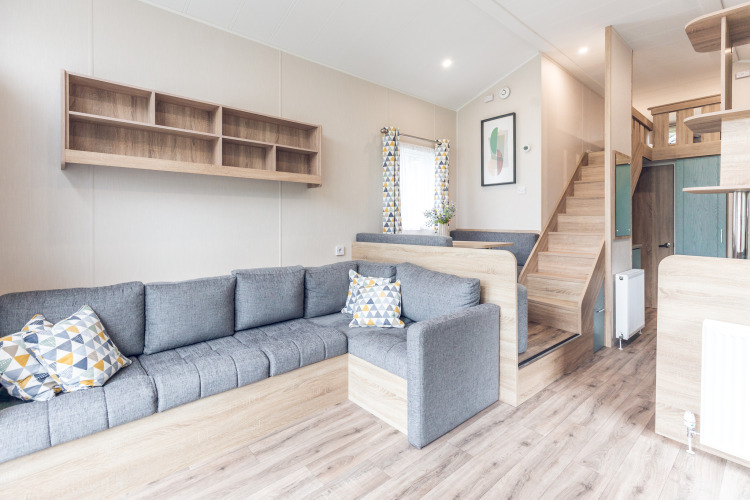 Sala moderna y luminosa en una tiny house en Holiday park Ackersate, con sofá gris y altillo arriba.