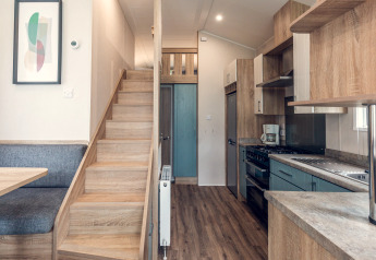 Modern tiny house at Holiday park Ackersate in the Netherlands featuring kitchen, staircase and dining area.