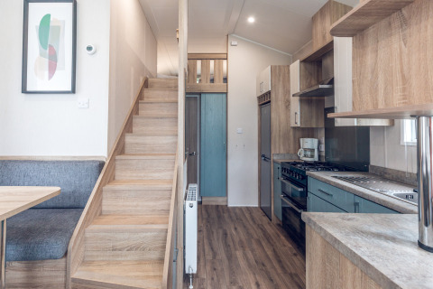 Modern tiny house at Holiday park Ackersate in the Netherlands featuring kitchen, staircase and dining area.
