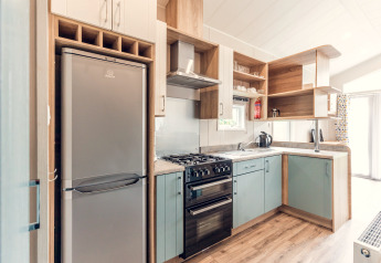 Modernes, kompaktes Kücheninterieur mit Kühlschrank, Ofen und Holzregalen in einer Lodge in den Niederlanden.