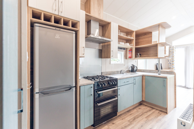Cocina moderna y compacta con frigorífico, horno y estanterías de madera en una casa pequeña en los Países Bajos.