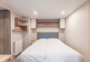 Dormitorio en una tiny house en Holiday park Ackersate, Países Bajos, con cama doble y muebles modernos.