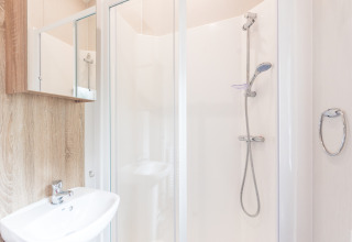 Moderne badkamer met douche, lavabo en spiegel in een Tiny House in Holiday park Ackersate, Nederland.