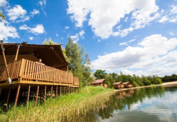 Wasser-Lodge im Ferienpark BreeBronne, Niederlande, auf Stelzen am See unter blauem Himmel.