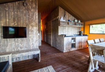 Vista interna del Water Lodge WL all’Holiday Park BreeBronne con arredi in legno e angolo cucina.