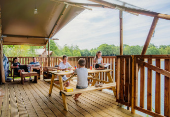 Familie entspannt sich und genießt Essen auf der Terrasse der Water Lodge WL im Holiday Park BreeBronne.