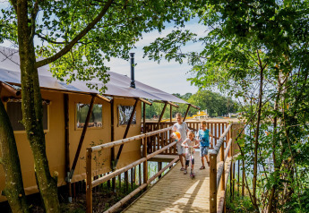 Famiglia cammina su passerella in legno presso Water Lodge WL, Holiday Park BreeBronne, Paesi Bassi.