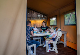 Familie genießt eine Mahlzeit in einer Holzhütte der Water Lodge WL im Holiday Park BreeBronne, Niederlande.